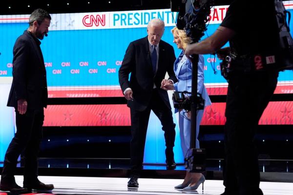 Biden walks down the stage steps while holding his wife's hand on June 27, 2024.